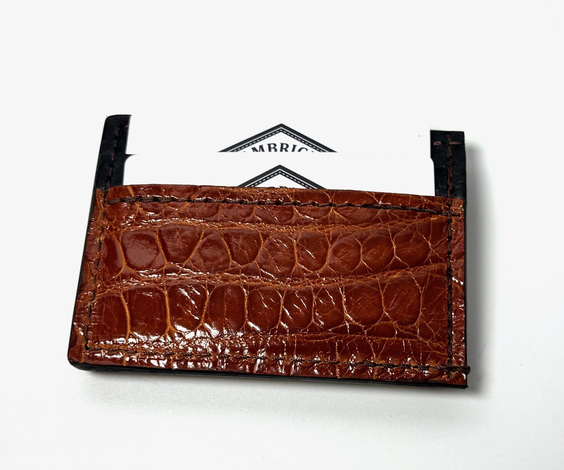 Back view of the cognac alligator leather money clip wallet with two cards inserted into the card pocket.