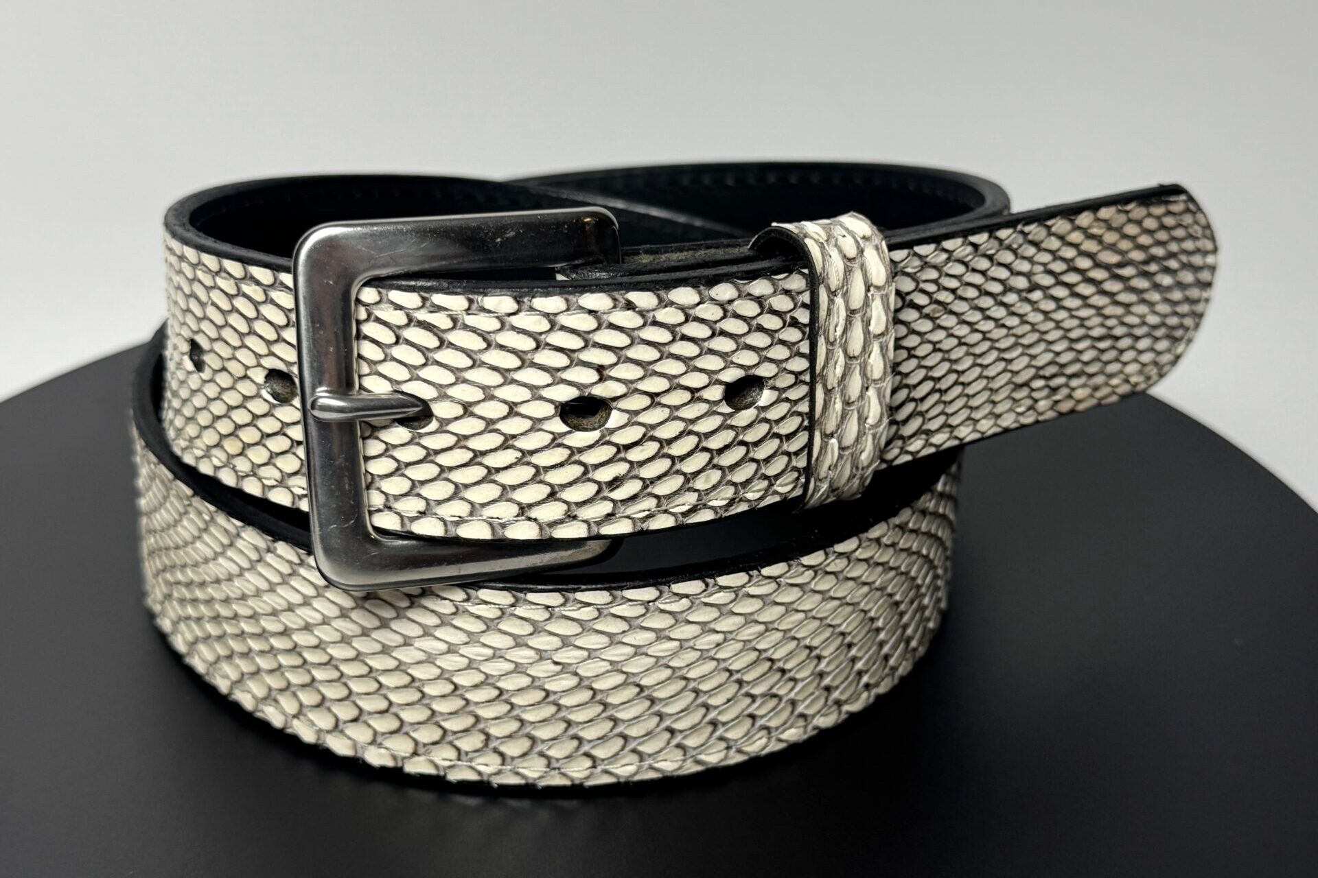 Rolled natural cobra leather belt showing black full-grain leather backing