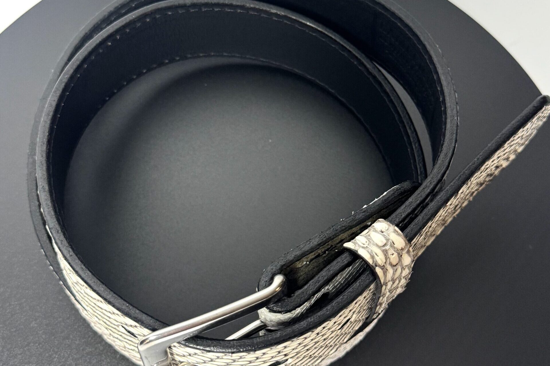 Angled view of natural cobra scale leather belt with black edges